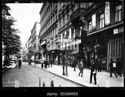 Eine Straße in Wien ist für die Trauer um Erzherzog Franz Ferdinand im Jahr 1914 dekoriert. In den Geschäften und öffentlichen Räumen sind Gedenkdekorationen nach seinem Attentat angebracht, die die Reaktion der Bürger und die urbanen Trauerbräuche widerspiegeln. Drücken Sie Foto. Stockfoto