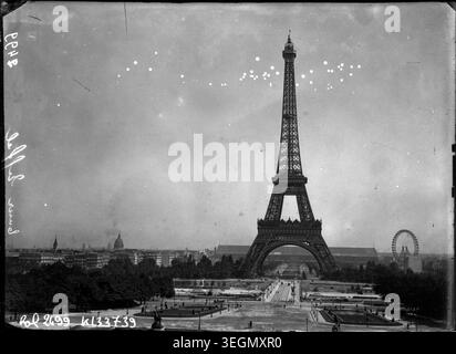 Der Eiffelturm steht mit dem Riesenrad auf der rechten Seite in Paris, fotografiert 1908. Das Pressefoto dokumentiert urbane Freizeitattraktionen, öffentliche Unterhaltung und Pariser Stadtbild im frühen 20. Jahrhundert. Stockfoto