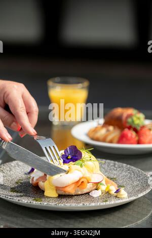 Herrlicher Brunch mit Eiern Benedict und frischem Obst in sonniger Umgebung im Freien Stockfoto
