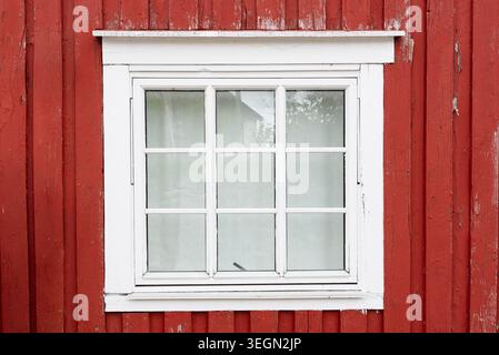 Weiß gerahmtes Fenster auf roter Holzfassade in traditioneller skandinavischer Architektur Stockfoto