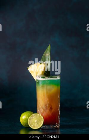 Erfrischendes tropisches Getränk garniert mit Ananas und Limette auf dunklem Hintergrund Stockfoto