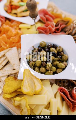 Lebhaftes Sortiment mit verschiedenen Käsesorten, Aufschnitt, Oliven und Brotstücken in lebhaften Farben Stockfoto