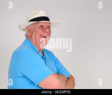 Der Mann trägt ein blaues Poloshirt und einen weißen Panama-Strohhut mit schwarzem Band. Er lächelt warm, die Arme überkreuzt. Der Hintergrund ist einfach weiß. Ausdruck zeigt Pommes frites an Stockfoto