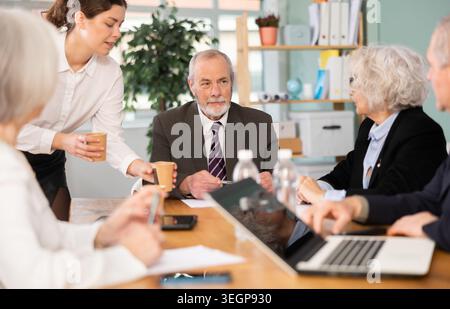 Ein älterer Mann führt ein Treffen mit Kollegen am Tisch Stockfoto