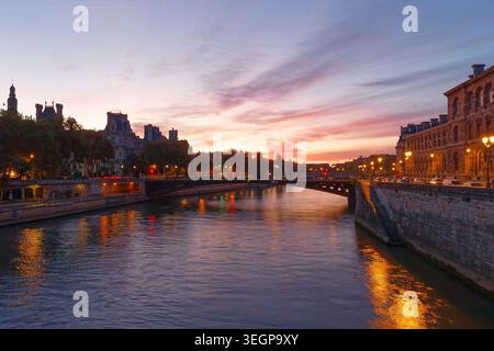 Atemberaubender Sonnenuntergang über der seine in Paris, mit der Silhouette des H tel de Ville im goldenen Wasser. Eine Steinbrücke überspannt den Stockfoto