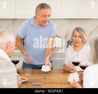 Gruppe von Freunden, die Poker-Karten spielen und zu Hause Wein trinken Stockfoto