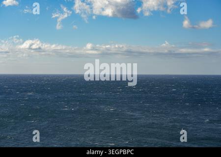 Blaues Ozeanwasser unter einem Himmel voller verstreuter Wolken Stockfoto