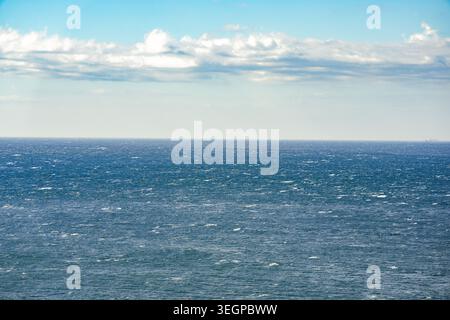 Blaues Ozeanwasser unter einem Himmel voller verstreuter Wolken Stockfoto