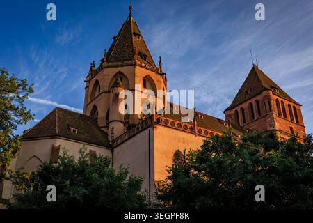 Das Leuchten des Sonnenuntergangs auf der Fassade der historischen St. Thomas Kirche aus rosa Sandstein in Straßburg, Frankreich Stockfoto