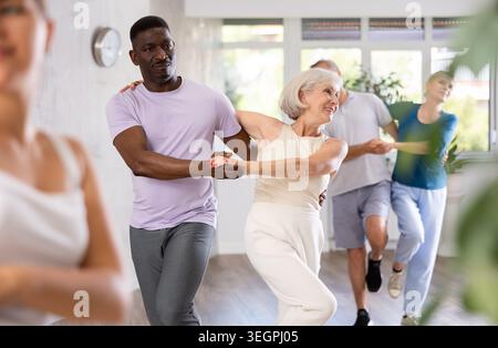 Ein Afroamerikaner tanzt dampfende Salsa mit einer älteren weiblichen Begleiterin für Fitnesskurse Stockfoto
