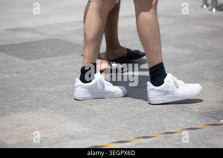 BANGKOK, THAILAND-13. MAI 2026: Männer in weißen Sneakers Stepping, nike Sneakers, offenes tropisches Straßenleben, Hochwinkelansicht Stockfoto
