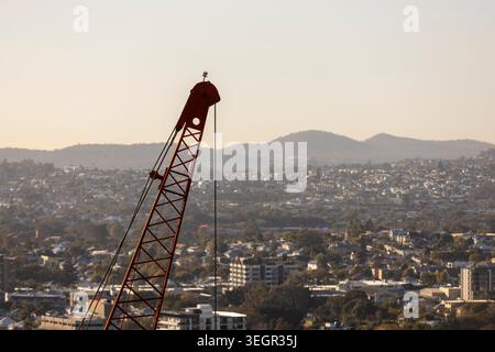 Ein markanter orangener Baukran ragt über weitläufigen Vororten in Brisbane, Queensland, Australien Stockfoto