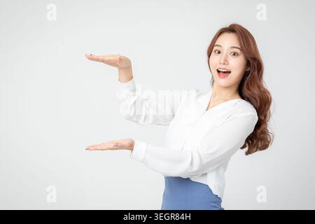 Eine Frau mit ausgestreckten Armen und einem großen Lächeln steht vor einem weißen Hintergrund. Stockfoto
