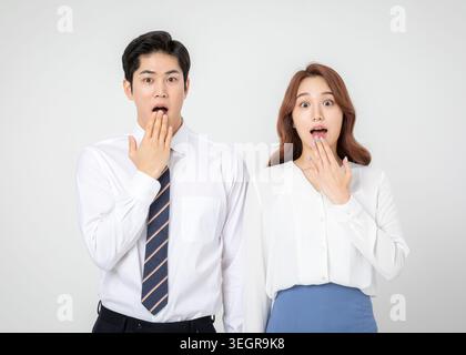 Ein Mann und eine Frau in Geschäftskleidung sind schockiert und verdecken den Mund. Stockfoto