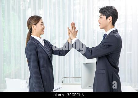 Zwei Geschäftskollegen in einem modernen Büro, die eine erfolgreiche Besprechung feiern. Stockfoto