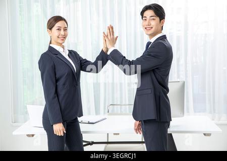 Zwei Kollegen in einem modernen Büro, die sich in einer freundlichen und feierlichen Atmosphäre lächeln. Stockfoto