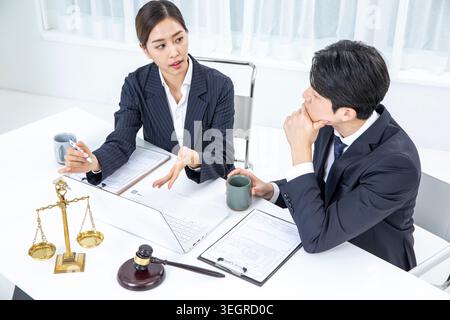 Zwei Kollegen, eine Frau und ein Mann, in einem Meeting, bei einem Kaffee in einem modernen Büro über Dokumente diskutieren. Stockfoto