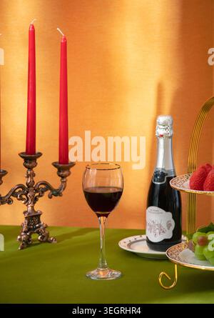 Ein Weinglas wird mit Rotwein gefüllt, in einem luxuriösen Ambiente bei Kerzenlicht. Stockfoto