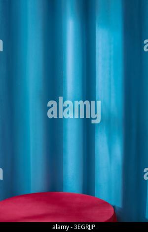 Ein roter Samttisch steht vor einem blauen Vorhang. Stockfoto