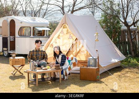 Ein junges Paar genießt ein romantisches Frühstück auf einem sonnigen Campingplatz. Stockfoto