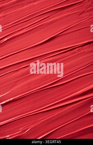 Eine Nahaufnahme roter, lebendiger Farbstriche auf einer Leinwand, die die Textur der Farbe freigeben. Stockfoto