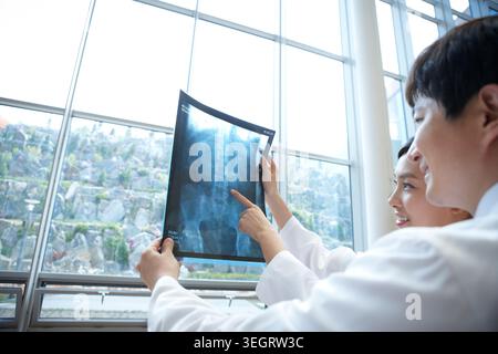Ärzte in einem weißen Morgenmantel diskutieren glücklich über ein Röntgenbild Stockfoto