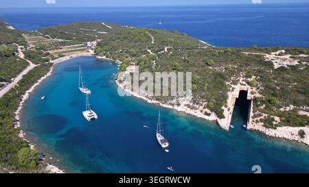 Blick aus der Vogelperspektive auf den Bootsunterstand Potkop Parja und Segelboote in einer türkisfarbenen Bucht, umgeben von üppigen grünen Hügeln in Rogacic, Splitsko-dalmatinska, Kroatien. Stockfoto