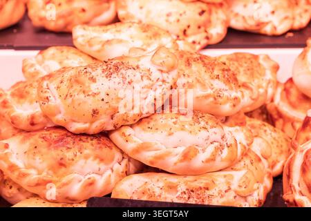 Nahaufnahme eines Haufens goldener, frisch gebackener traditioneller spanischer Empanidas oder herzhafter Gebäck mit goldener Kruste in der berühmten Publi La Boqueria Stockfoto