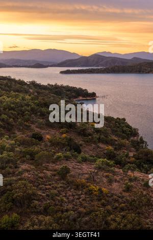 Vertikale Luftaufnahme des Glenbawn Dam bei Sonnenuntergang in NSW Australien. Das Drohnenfoto erfasst ruhige Dammgewässer, umliegende Hügel und den farbenfrohen Himmel. Stockfoto