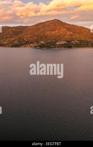 Vertikale Luftaufnahme des Glenbawn Dam bei Sonnenuntergang in NSW Australien. Das Drohnenfoto erfasst ruhige Dammgewässer, umliegende Hügel und den farbenfrohen Himmel. Stockfoto