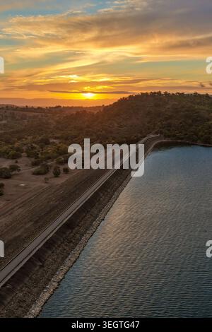 Vertikale Luftaufnahme der Glenbawn Dam Mauer, die zu einem Sonnenuntergang über der umliegenden Bergkette in NSW Australien führt. Drohnenfotografie. Stockfoto