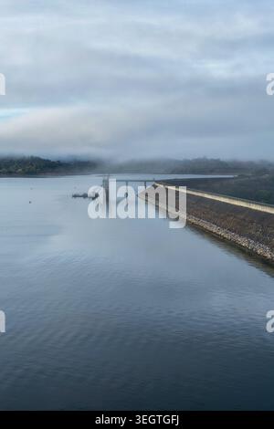 Vertikale Luftaufnahme der Glenbawn Dam Mauer und der umliegenden Landschaft mit Nebel, der durch das Tal in NSW Australien fließt. Drohnenfotografie Stockfoto