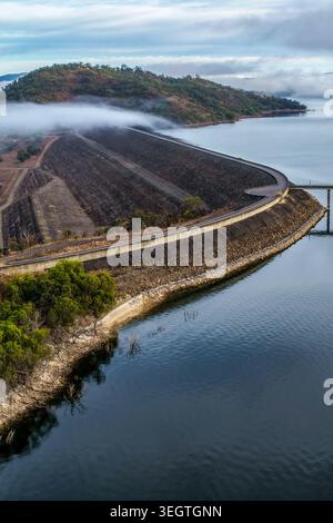 Vertikale Luftaufnahme der Glenbawn Dam Mauer mit Wassereinlasssystem und wartendem Ponton mit Nebel, der über das Wasser in NSW schwimmt Stockfoto