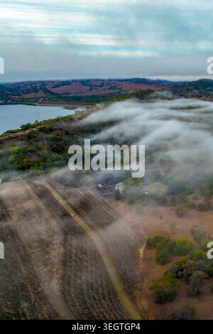 Vertikales Luftbild der Glenbawn Dam Mauer mit Morgennebel, der durch das umliegende Tal in NSW Australien driftet. Drohnenfotografie Stockfoto