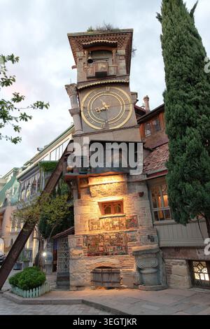 Berühmter Schiefer Uhrenturm des Rezo Gabriadze Marionettentheaters mit goldenem Zifferblatt in der Abenddämmerung, Tiflis, Georgien - 29. April 2026. Stockfoto