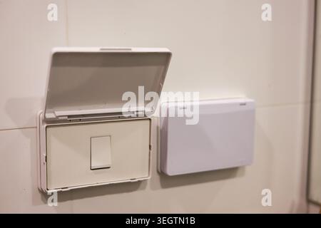 Weiße, wasserdichte Abdeckung für elektrische Schalter zur Wandmontage bietet Sicherheit in Badezimmerumgebungen mit zuverlässiger, sicherer und offener Kunststoffkonstruktion Stockfoto