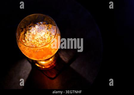 Blick von oben auf Glas gefüllt mit kaltem Whiskey-Getränk und zerstoßenem Eis auf dunklem Hintergrund, was eine einladende entspannende Stimmung schafft Stockfoto