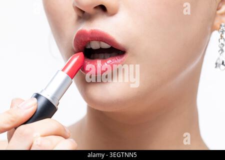 Eine Frau trägt in Nahaufnahme einen roten Lippenstift auf ihre Lippen. Stockfoto