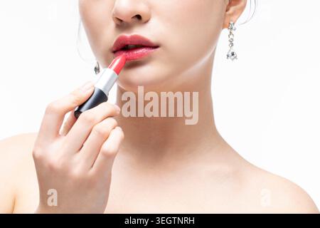 Eine Frau trägt Lippenstift in einem weißen Studio. Stockfoto