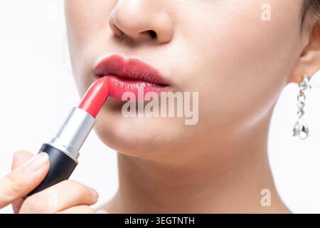 Eine Frau trägt einen hellroten Lippenstift auf ihre Lippen. Stockfoto