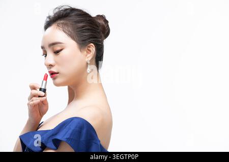 Eine junge Frau trägt Lippenstift in einem Studio-Setting. Stockfoto