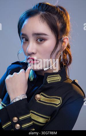 Eine junge Frau in einer Jacke im Militärstil schaut mit ernstem Ausdruck direkt in die Kamera. Stockfoto