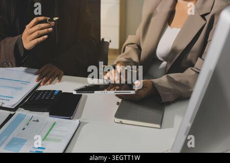 Zwei junge asiatische Geschäftsfrauen diskutieren über die Arbeits- und Planungsstrategie von Investitionsprojekten. Ein Buchhalter bringt einem Lehrling die Arbeit bei. Stockfoto