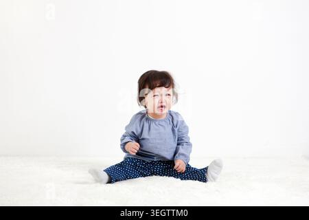 Ein Baby sitzt auf dem Boden und posiert Stockfoto