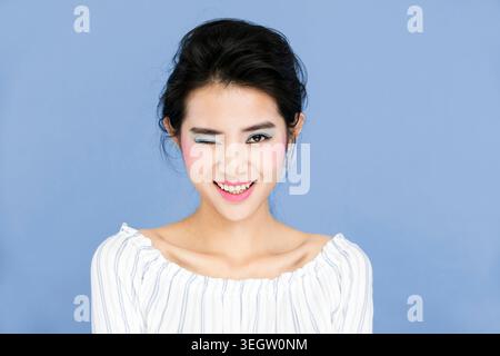 Porträt des jungen lächelnde Frau zwinkert Stockfoto