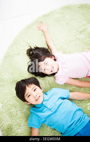 Porträt von lächelnden jungen und Mädchen auf einem Teppich hinlegen Stockfoto