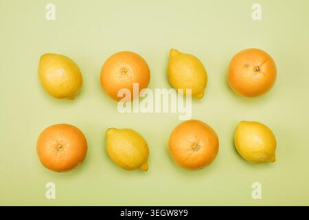 Eine Reihe von Zitronen und Orangen auf einer hellgrünen Oberfläche. Stockfoto