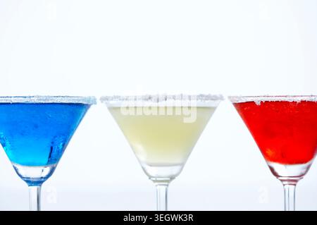 Eine Reihe von drei farbenfrohen Cocktails, jeder in einem Martini-Glas, nebeneinander angeordnet. Stockfoto