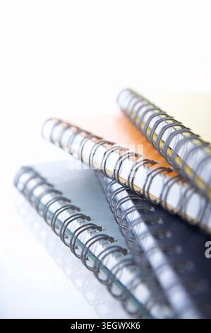 Ein Stapel spiralgebundener Notizbücher liegt auf einer weißen Oberfläche. Stockfoto