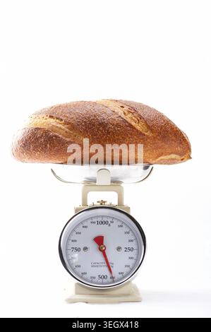 Ein frisch gebackener Brotlaib wird auf einer Küchenwaage gewogen. Stockfoto